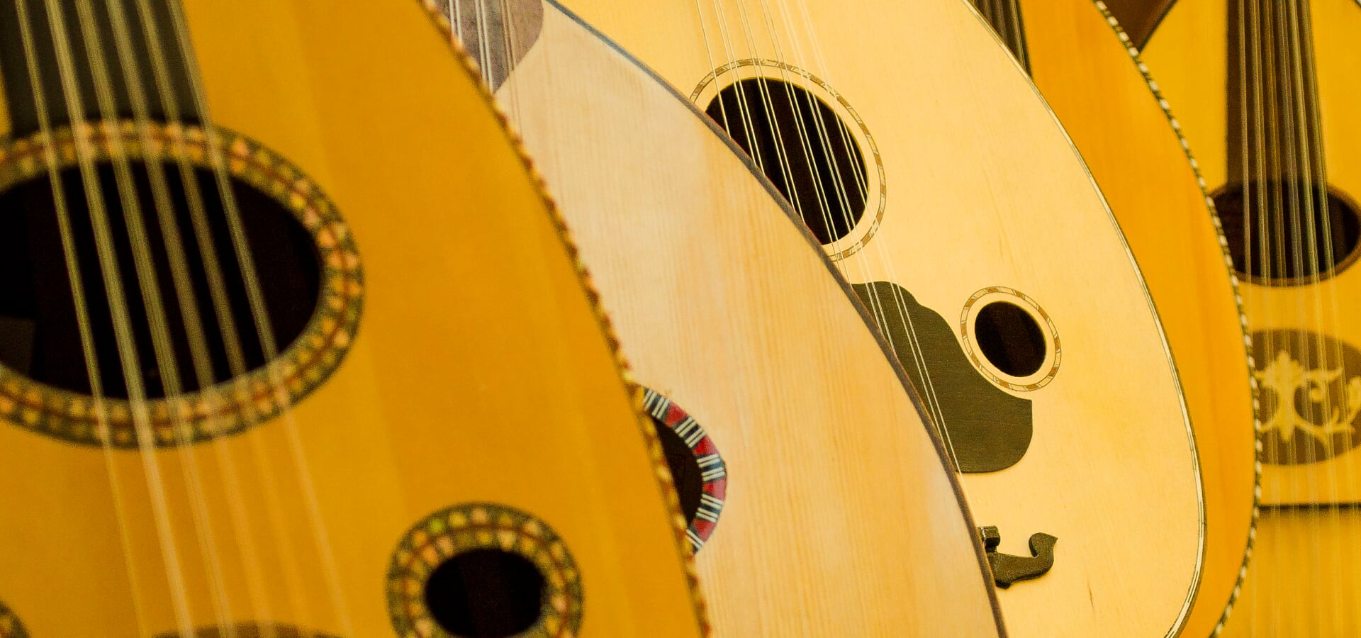A student's hand fretting the oud during a lesson.